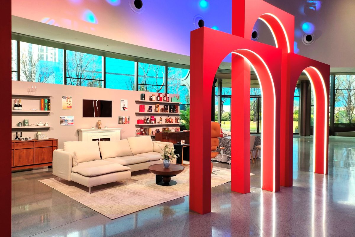 The living room with cross-merchandised product displays is framed with a group of modern red arches;
Image Source: 5 Star Plus Retail Design